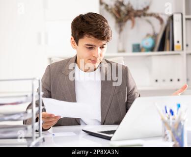Male bookkeeper doing paperwork in workplace in office - checks accounting documents Stock Photo
