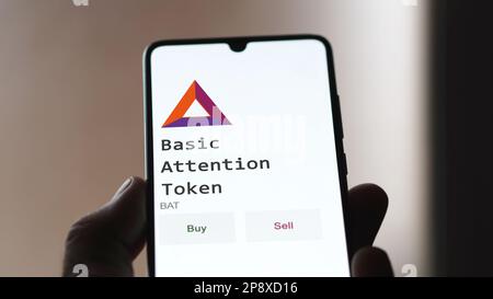 An investor's analyzing the Basic Attention Token ( BAT ) coin on screen. A phone shows the crypto's prices to invest in amp token. Stock Photo