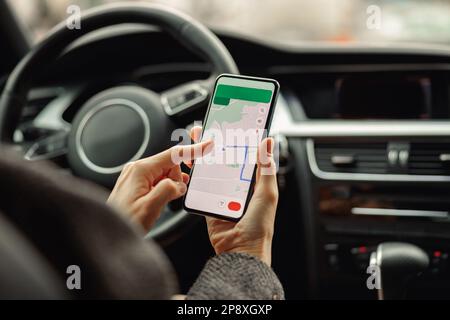 Closeup of female traveler using cell phone with gps navigation app on screen while sitting in car Stock Photo