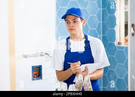 Young builder making checklist while planning indoor building overhaul Stock Photo
