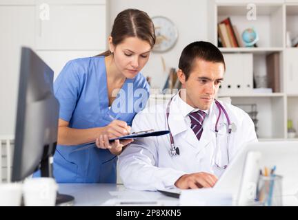 Two physicians working with case histories on laptop Stock Photo