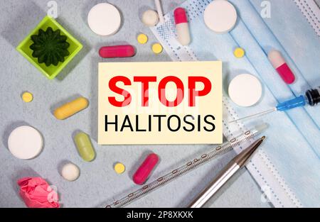 On a blue background ampoule with medicines and a notebook with the text STOP HALITOSIS. Medical concept Stock Photo