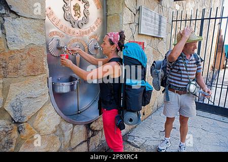 Pilgrims filling a glass of wine in Winery Irache. fountain that offers water and wine to the pilgrim. Irache. Navarra.Spain. Camino de Santiago Stock Photo