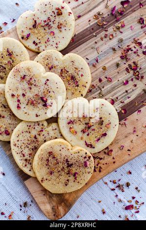 Heart shaped cookies on a tray sprinkled with rose petals. Stock Photo