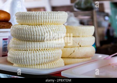 Georgian Sulguni cheese round discs stack on a market stall in Kutaisi Central Market (Green Bazaar,  Mtsvane Bazari). Stock Photo