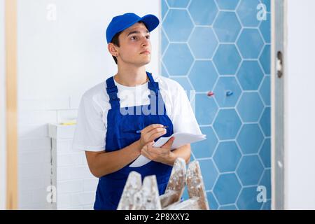 Young builder making checklist while planning indoor building overhaul Stock Photo