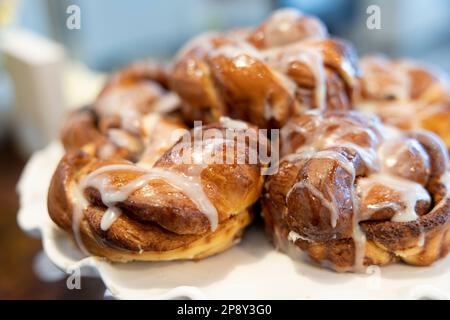 Cinnamon buns with white icing stacked on a white plate Stock Photo