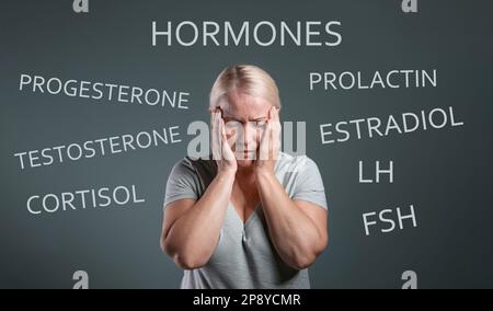 Hormones imbalance. Upset mature woman and different words on grey background Stock Photo