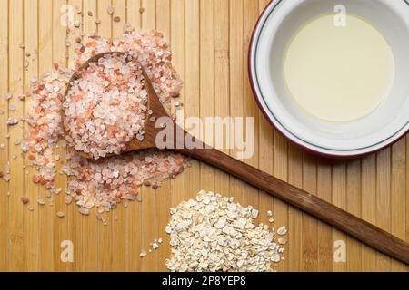 A flatlay photo of a wooden spoon with himalayan pink sea salt, dried oats, and a bowl of olive oil in a studio setting. Stock Photo