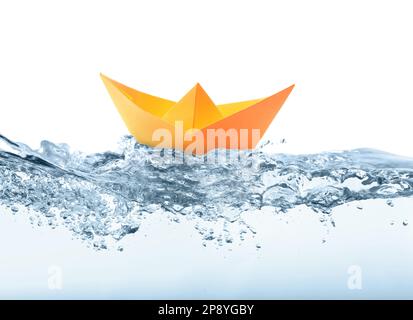Handmade orange paper boat floating on clear water against white background Stock Photo