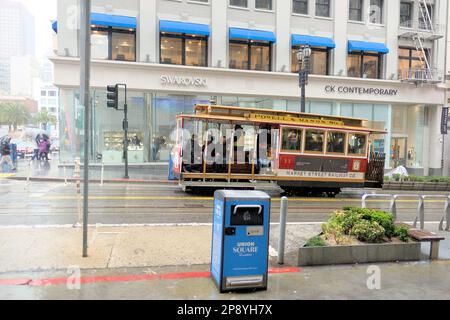 Tourists and visitors on a trolley in the rain in downtown San Francisco, California; people in rainy conditions and wet weather. Stock Photo
