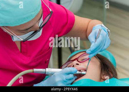 Dentist doing a dental cleaning to a girl, in his dental office Stock Photo