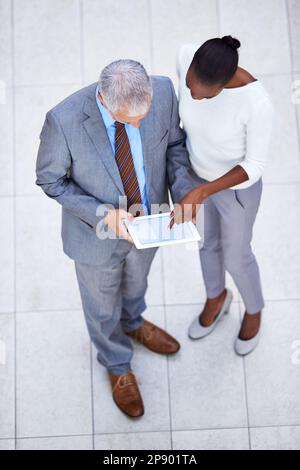 Using technology to manage their projects. High angle shot of two business colleagues standing with a digital tablet. Stock Photo