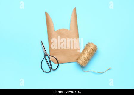 Easter bunny gift bag, scissors and thread on blue background Stock Photo