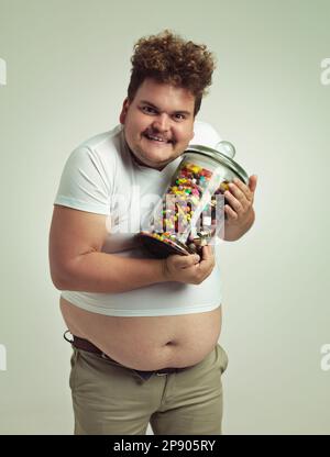 I love candy, can you tell. an overweight man holding a pot of candy. Stock Photo