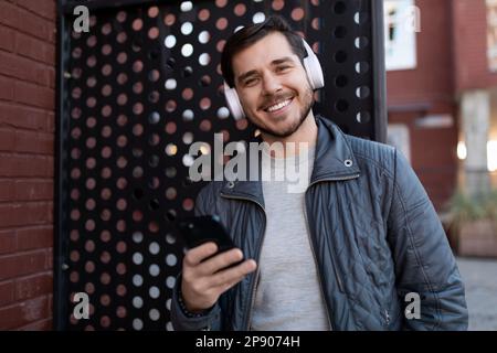 successful european male freelancer listening to podcast with headphones outdoors Stock Photo