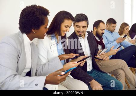 Group of happy friends using cellphones and sharing funny things from social media Stock Photo