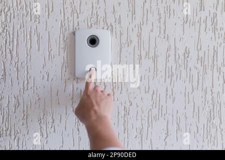 Close-up photo. The finger of a man's hand presses the button of the incoming call of the door, the camera. Electric lock to office, home, delivery Stock Photo