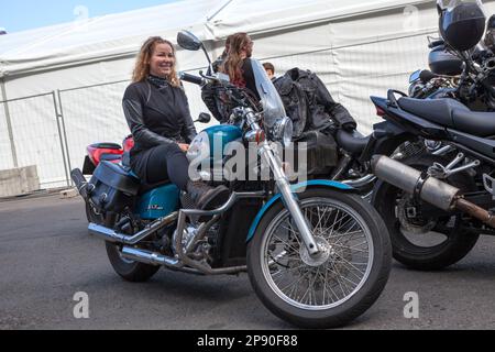 Saint-Petersburg, Russia-circa Aug, 2018: Happy girl motorcyclist sits on her bike during the celebration of the opening of the motorcycle season Stock Photo