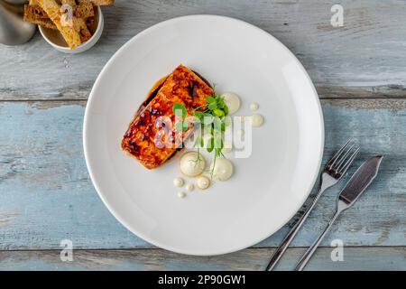 Grilled salmon fillet with sauces next to it on a white porcelain plate Stock Photo