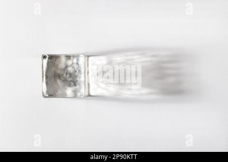 Top view of transparent shining ice cube with shadow placed on white background Stock Photo