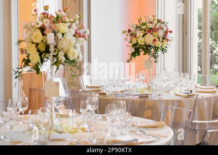 Elegant wedding banquet setting tables with glassware and blooming flowers in vases against window Stock Photo