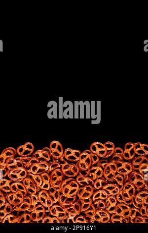 Border of mini pretzels on black background. Dark backdrop with Salted snacks Stock Photo