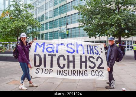 London, United Kingdom. 2nd September 2021. Protesters hold a banner as two HS2 protesters (background) scale Marsh Insurance offices in the City of London, demanding they stop insuring the HS2 (High Speed 2) railway system. Stock Photo