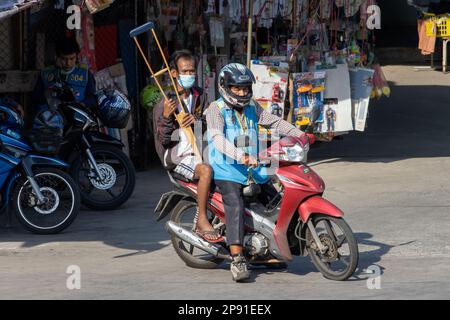 SAMUT PRAKAN, THAILAND, FEB 13 2023, A man with crutches rides with a moto taxi Stock Photo