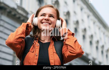 Happy smiling woman in headphones in city. Stock Photo