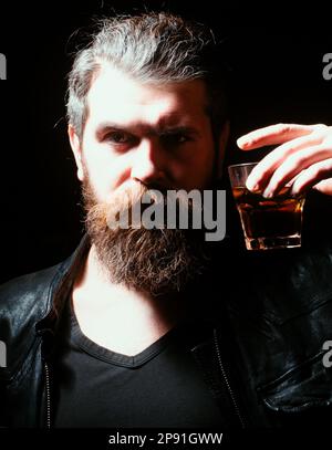 Man drinking whiskey, brandy, cognac. Man with glass of brandy. Bearded hipster with glass of whiskey. Old traditional whiskey drink - gentlemans Stock Photo