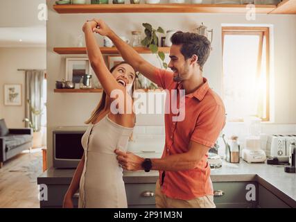 Joyful, dancing and loving couple bonding and having fun in the kitchen together at home. Energetic, fun and active relationship sharing a dance and Stock Photo