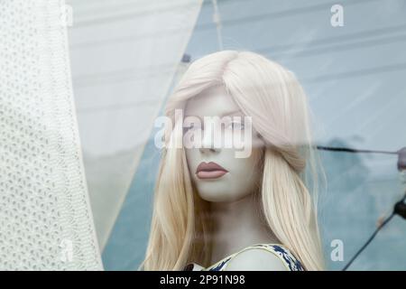 Cute realistic female mannequin face close-up in a shop window. Beautiful Caucasian manikin head with blonde hair Stock Photo