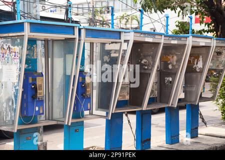 Row of old dirty payphones on a street in Thailand. Group of blue messy telephone booths in a city Stock Photo