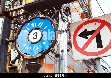 Street sign PATTAYA 3 in English and Thai next to a NO LEFT TURN sign. Stock Photo