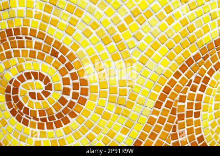 Yellow swirl pattern tiled bathroom wall. Mini square orange tiles background Stock Photo