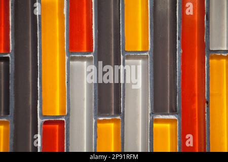 Colorful glass vertical rectangular tiled wall close-up: yellow, red, white, black pattern. Multicolor tiles Stock Photo