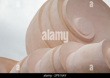 Decorative architecture detail in a spiral shape. Abstract gray and rose color concrete sculpture close-up background Stock Photo