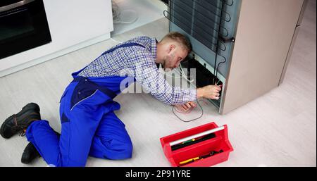 Testing Electric Appliance Using Multimeter To Repair Fridge At Home Stock Photo