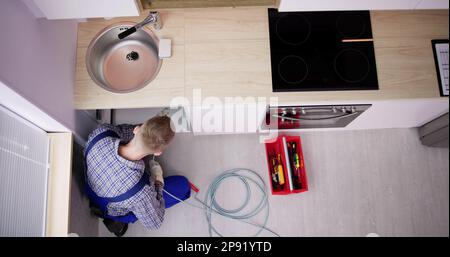 Plumber Drain Cleaning Services In Kitchen. Unclog Blocked Pipe Stock Photo