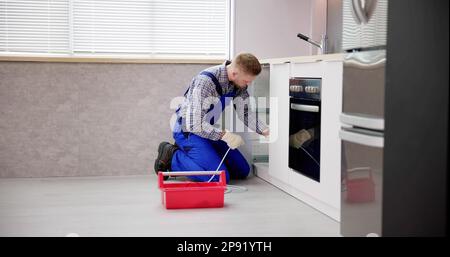 Plumber Drain Cleaning Services In Kitchen. Unclog Blocked Pipe Stock Photo