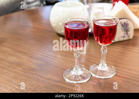 Two glasses of cranberry tincture stand on the wooden table, close up photo with selective soft focus Stock Photo