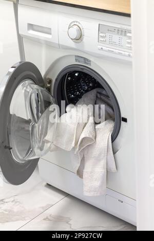 Open washing machine or clothes dryer with washed and dried white towels Stock Photo