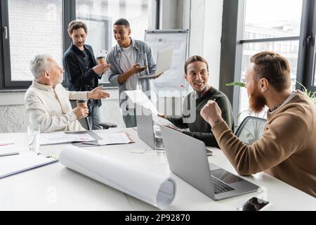Interracial business people discussing project and using laptops during meeting in office,stock image Stock Photo