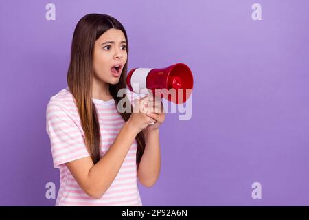 Photo of shocked impressed girl dressed striped t-shirt screaming toa empty space isolated purple color background Stock Photo