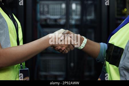 Youve got a deal. Cropped shot of two unrecognizable female programmers shaking hands in a server room. Stock Photo