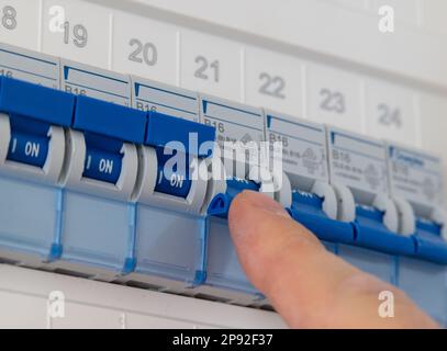 Technician switches on several fuse in a fuse box of a private house. Stock Photo