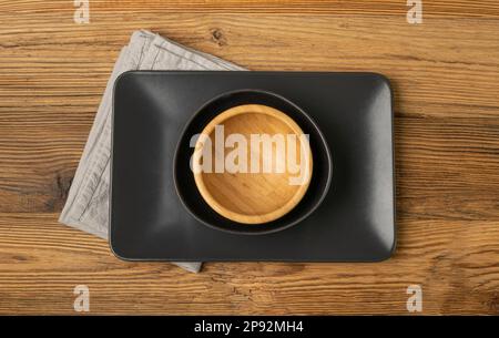 Empty Black Bowls and Wood Plates on Wooden Table Background, Black Plate Mockup Top View, Rustic Kitchen Mock Up with Copy Space Stock Photo