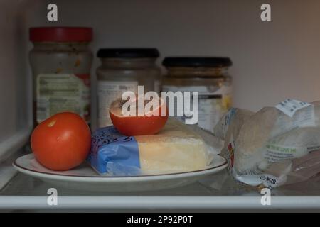 Forgotten food, tomato on a plate in fridge begins to decay having been infected by a pin mold most likely penicillin bacillus, lots of ripe spores Stock Photo