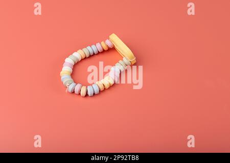 Tablet Candies Bracelet, Compressed Sugar Powder Confectionery, Dextrose Candy Necklace Parts, Lozenges on Pink Background Stock Photo